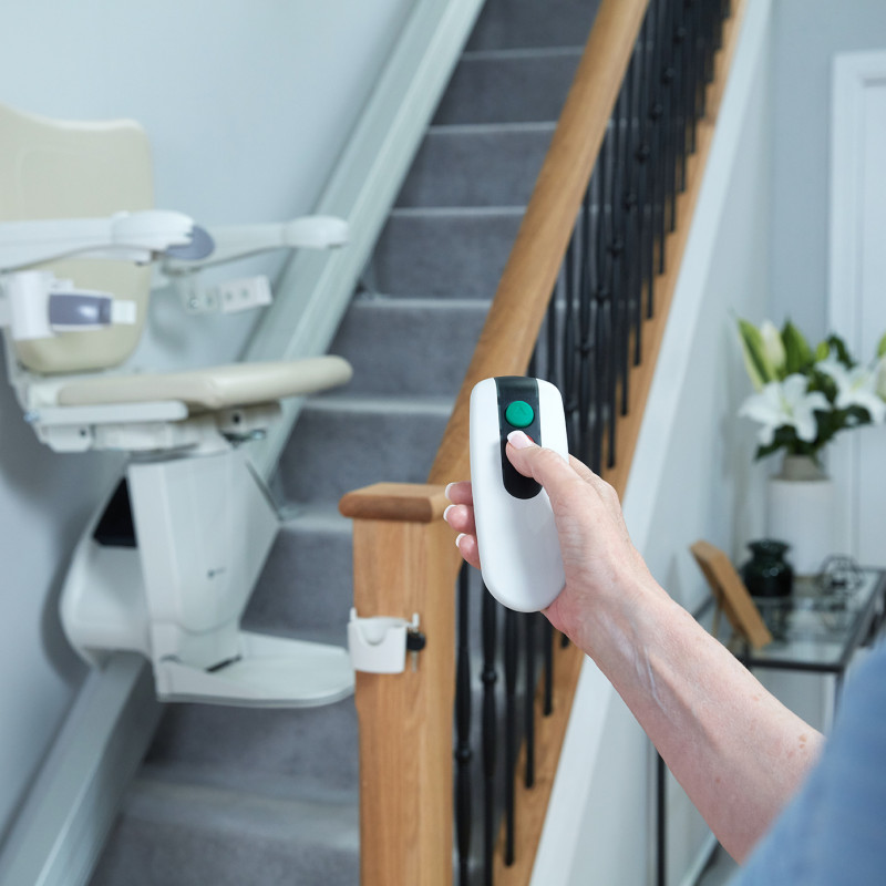 A woman using a remote control for a stairlift