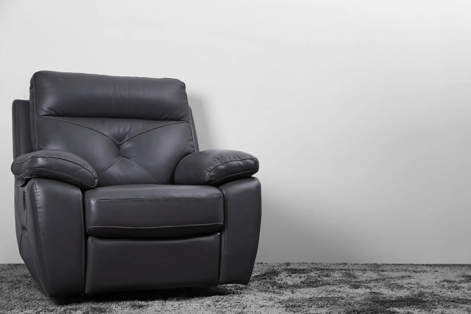 A black leather chair in front of a grey background