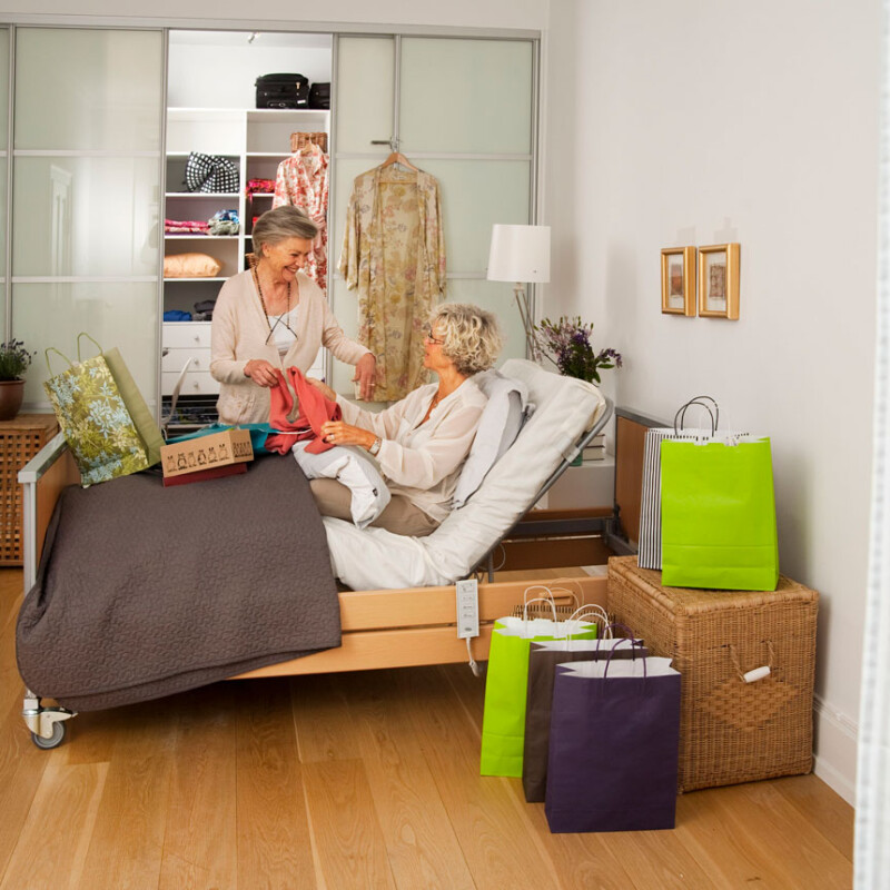 Two women in conversation discussing clothes with a reclining bed