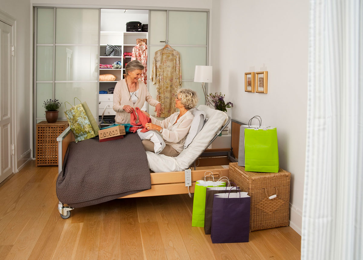 Two women in conversation discussing clothes with a reclining bed