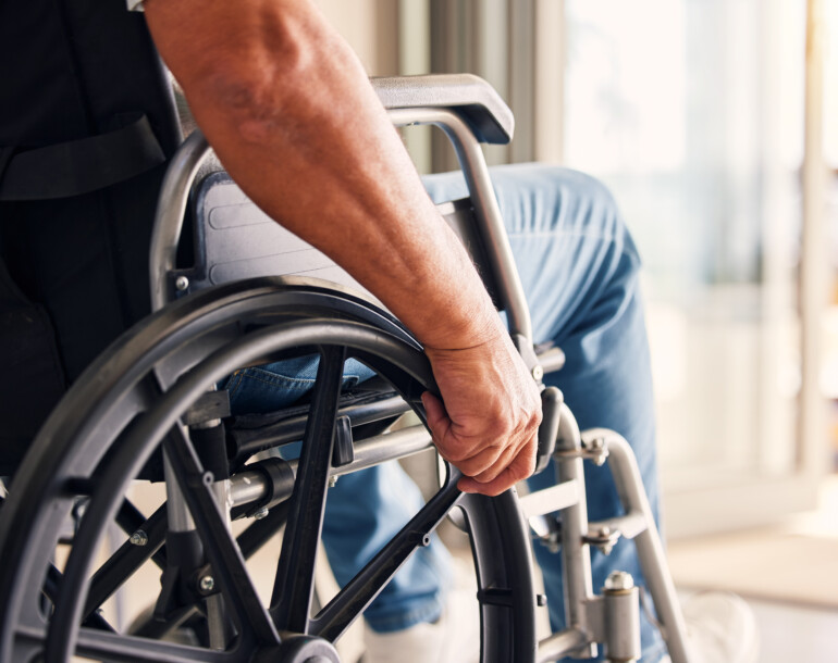 A zoomed in picture of a man holding onto the wheels of a wheelchair