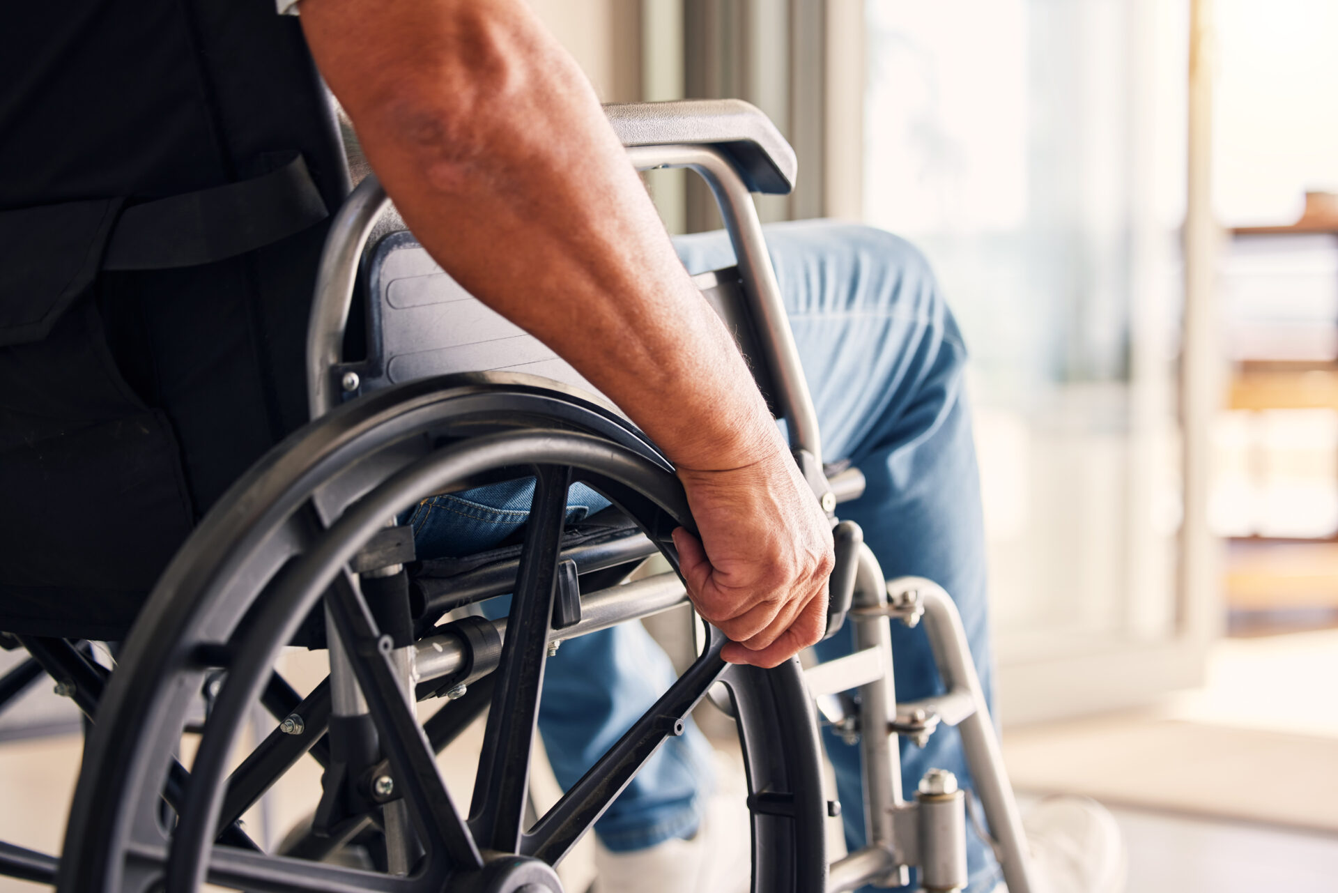 A zoomed in picture of a man holding onto the wheels of a wheelchair