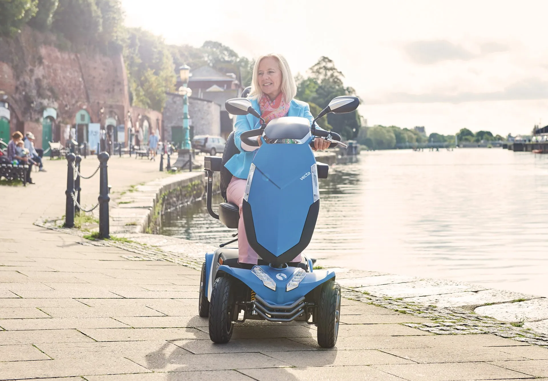 A woman on a blue mobility scooter next to a river